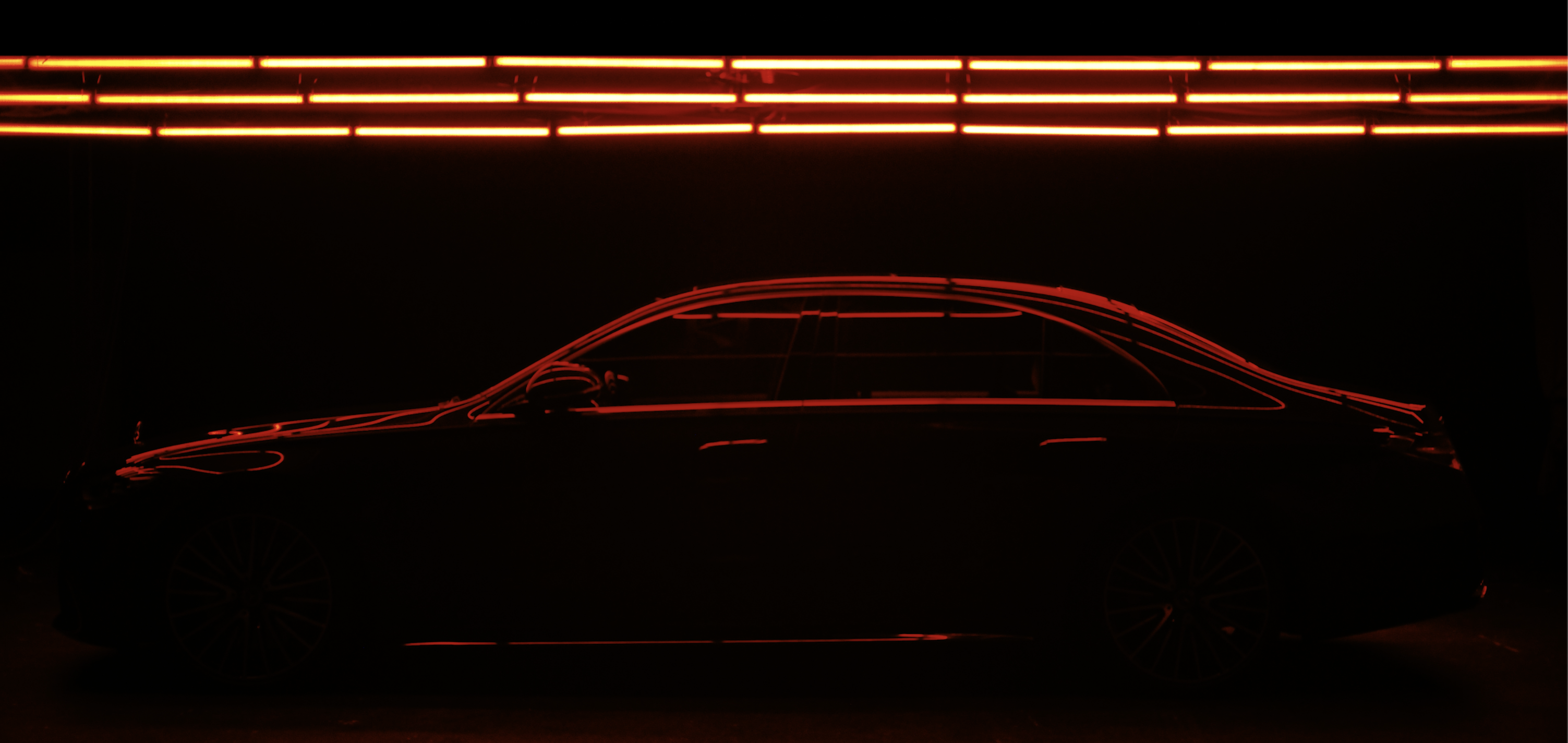 Mercedes-Benz S-Class silhouette outlined by dramatic red studio lighting.