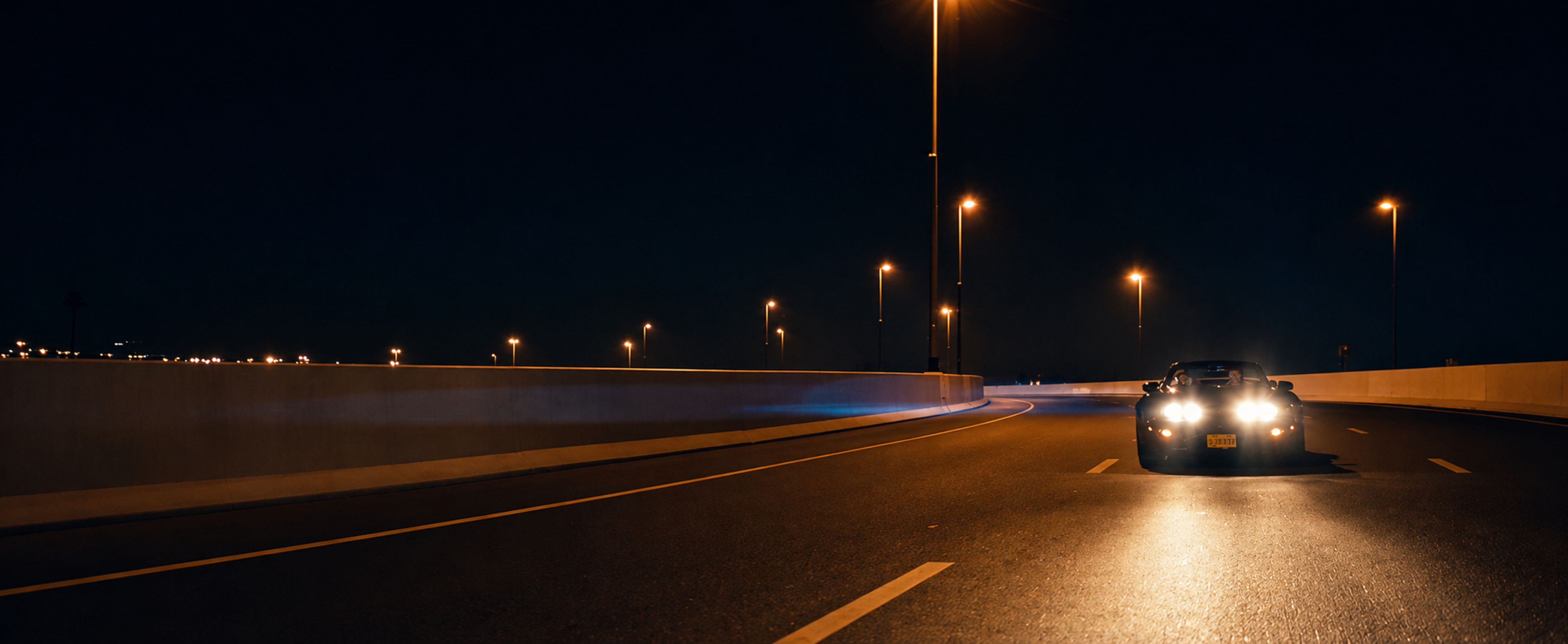Luxury car driving on a Dubai highway at night.