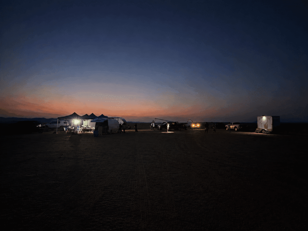 Behind-the-scenes desert production basecamp at twilight