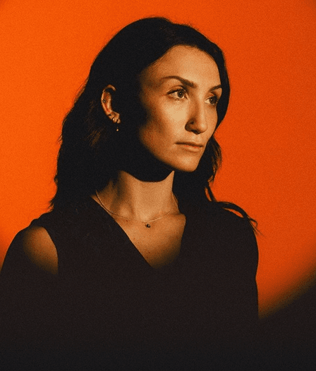 Portrait of Leila Haddad against a warm orange background.