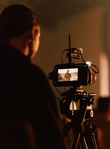 Portrait of Sofia Almeida filmed behind the camera on a warmly lit production set.