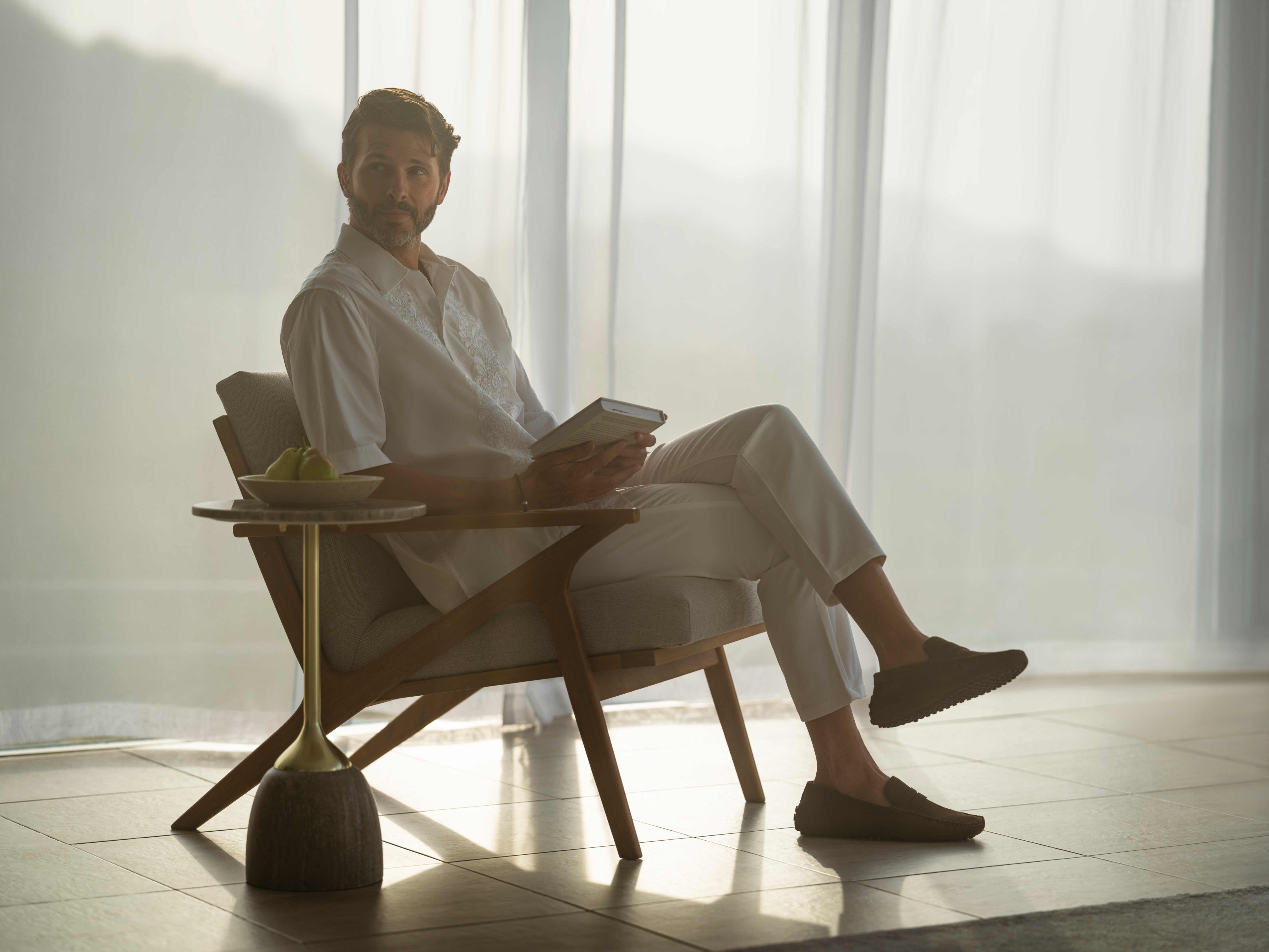 Man relaxing in a luxury interior with a book and natural light