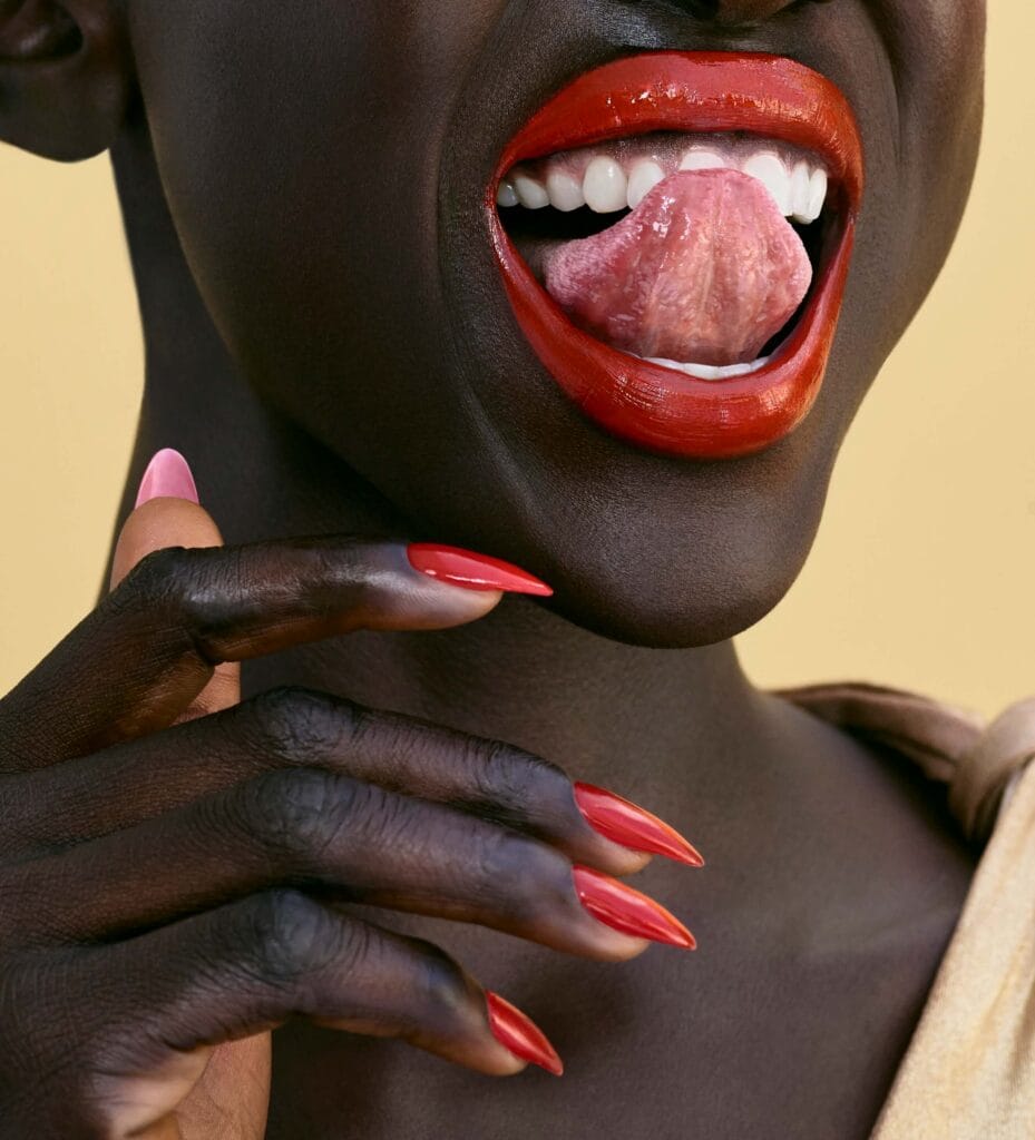 Emolyne Cosmetics beauty campaign close-up featuring glossy red lips and matching red manicure.