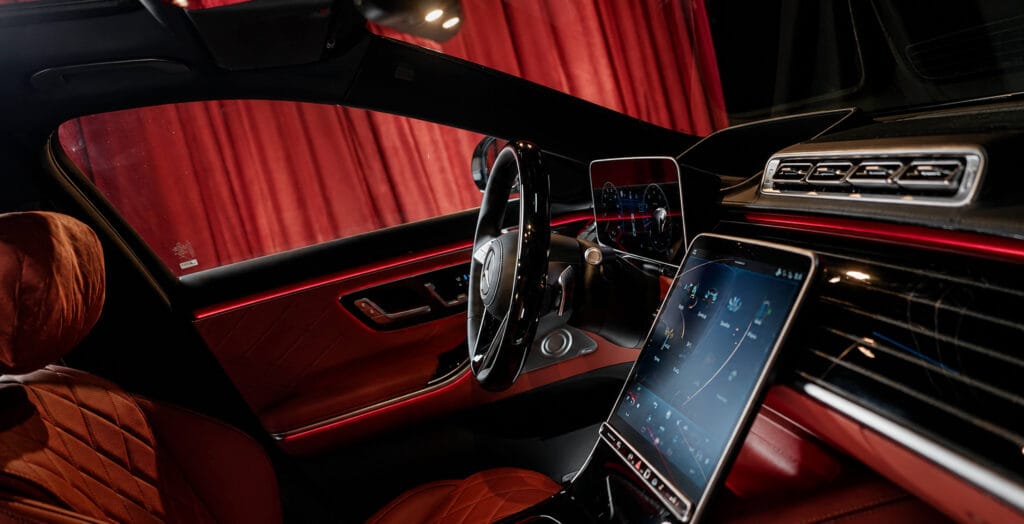 Mercedes-Benz S-Class luxury interior with red leather, ambient lighting and digital displays.