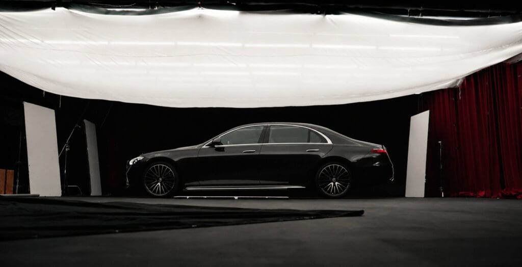 Mercedes-Benz S-Class side profile during a studio production setup with overhead diffusion and lighting.