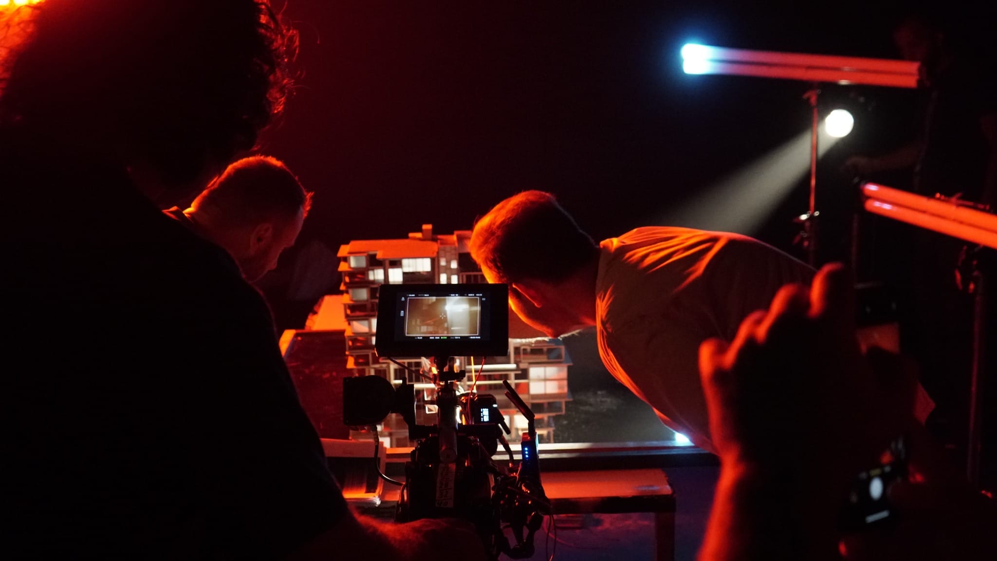 Film crew shooting the Six Senses residence miniature under dramatic red studio lighting.