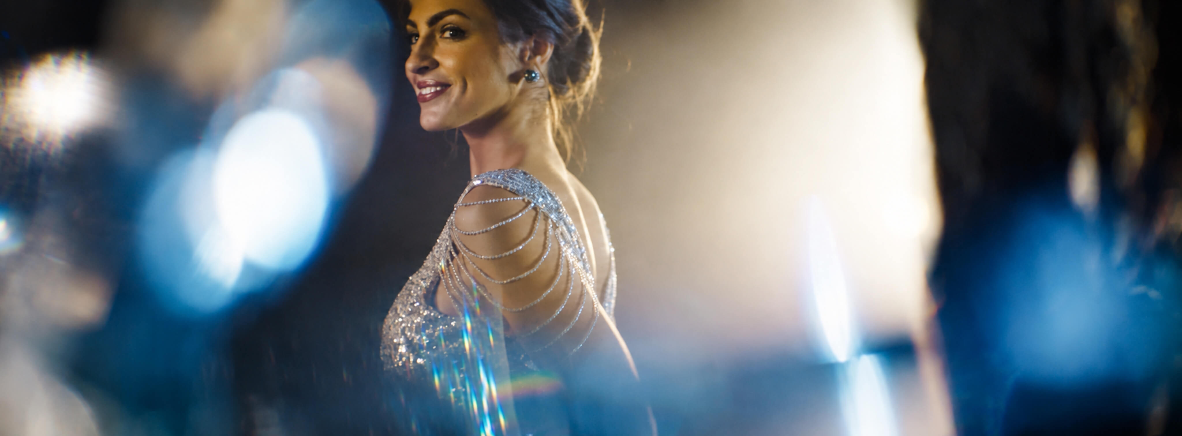Woman in a sparkling evening gown captured with cinematic light flares for the Six Senses campaign.