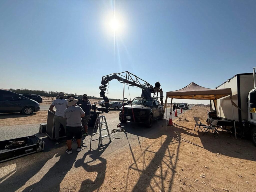 Automotive film production with camera crane rig on desert road set.
