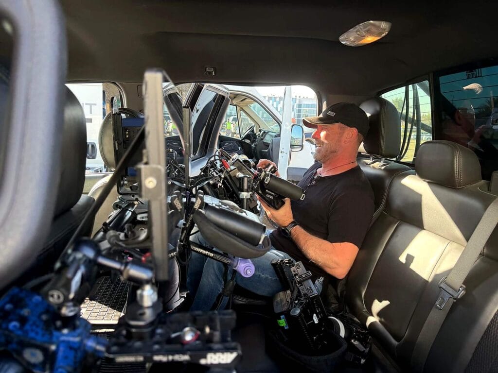 Camera technician working inside a production vehicle with professional filming equipment
