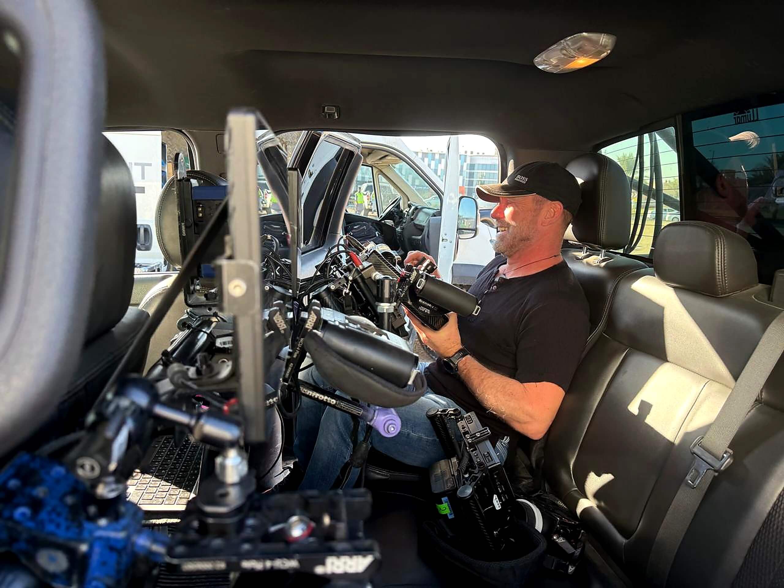 Camera technician working inside a production vehicle with professional filming equipment