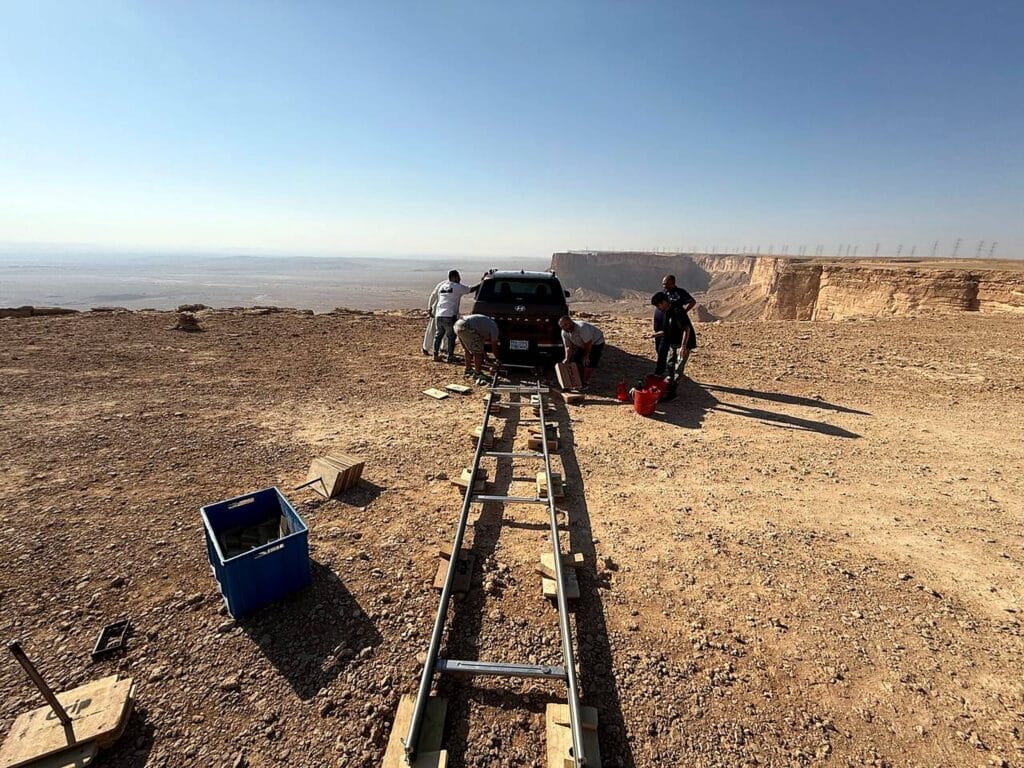 Film crew setting up a camera dolly track in a desert location