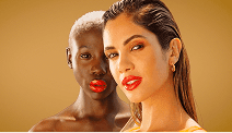 Two women posing together against a warm golden background, wearing bold red lipstick