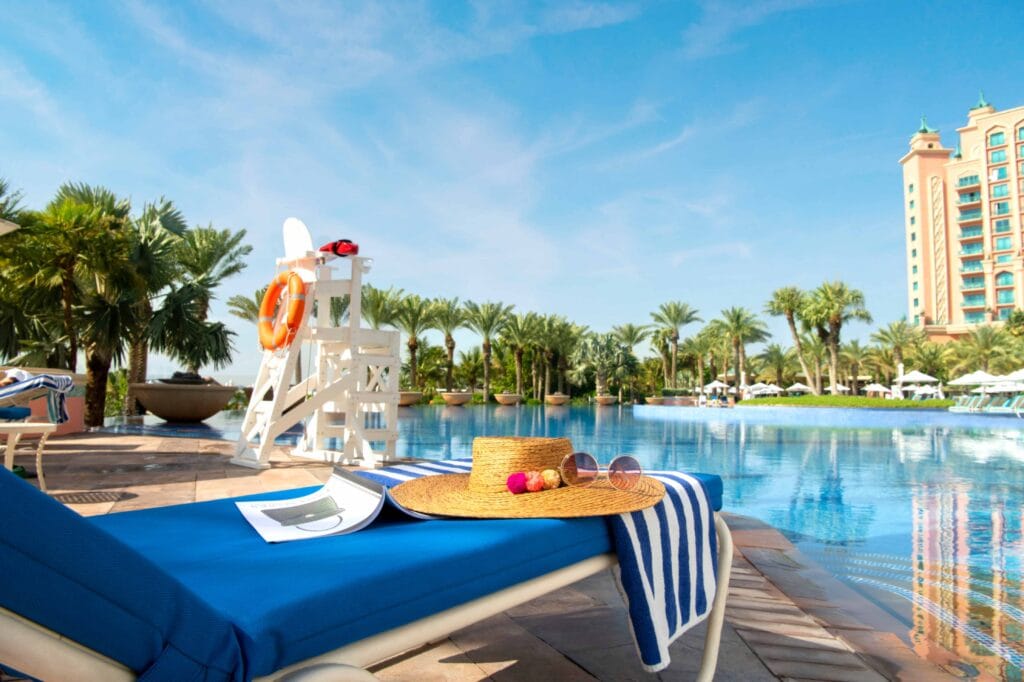 Atlantis Aquaventure resort pool in Dubai with a sun lounger, hat and palm trees.