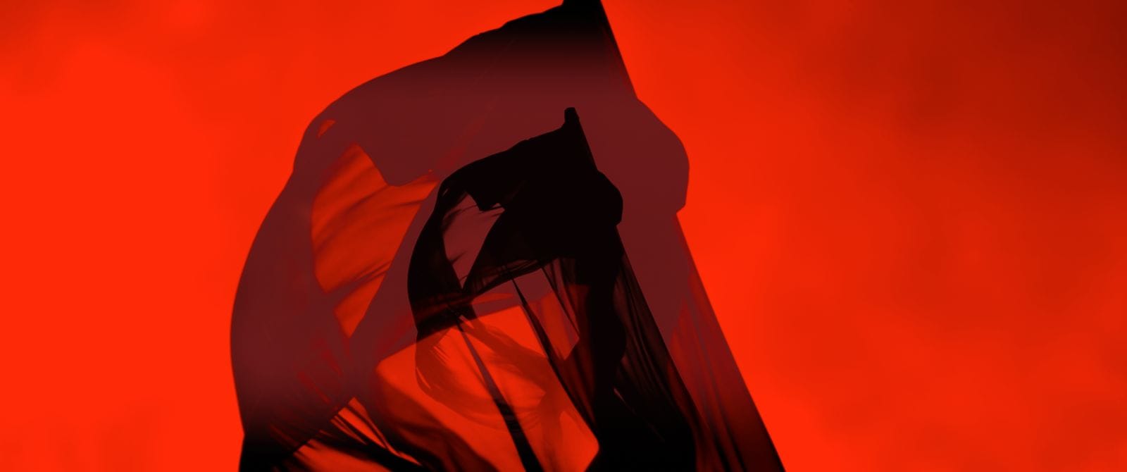 Abstract model silhouette beneath flowing red fabric in the Ayan Beauty campaign film