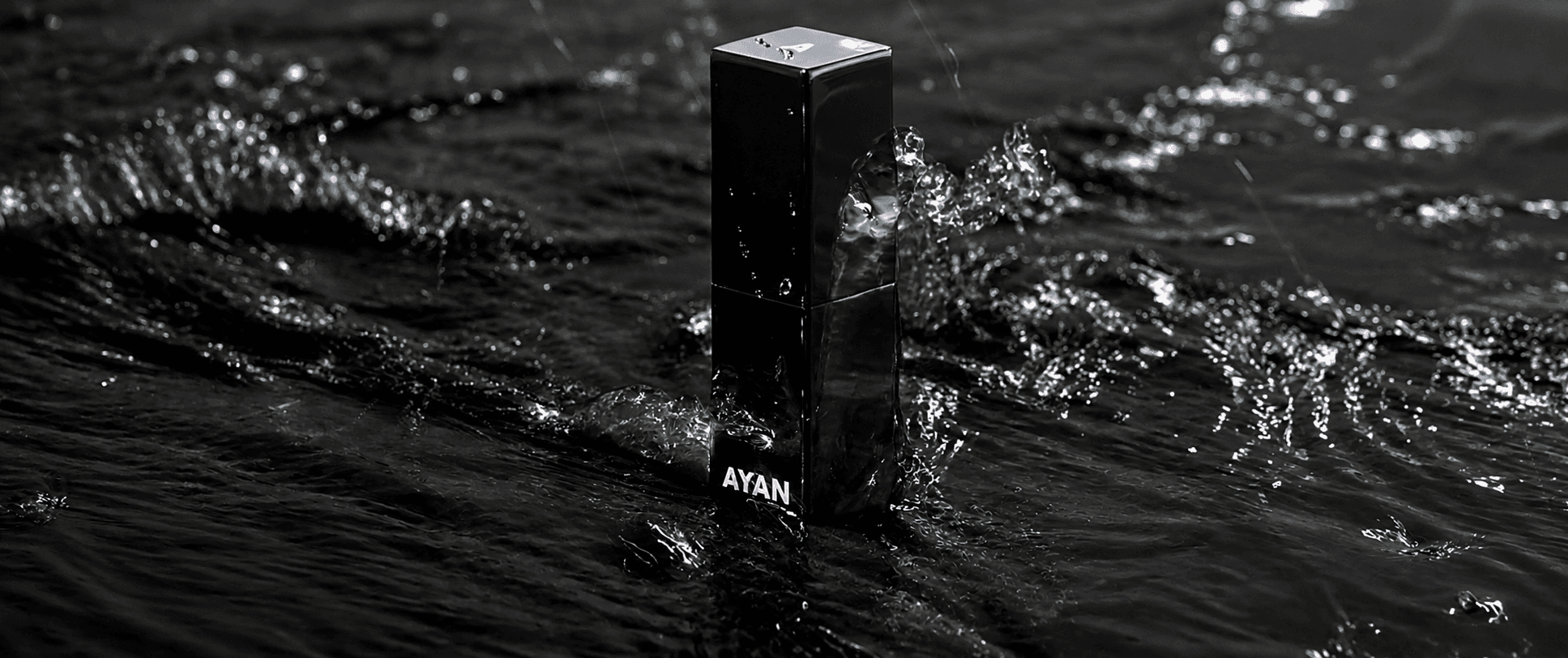 Ayan Beauty black lipstick case standing in rippling water in a monochrome luxury product shot.