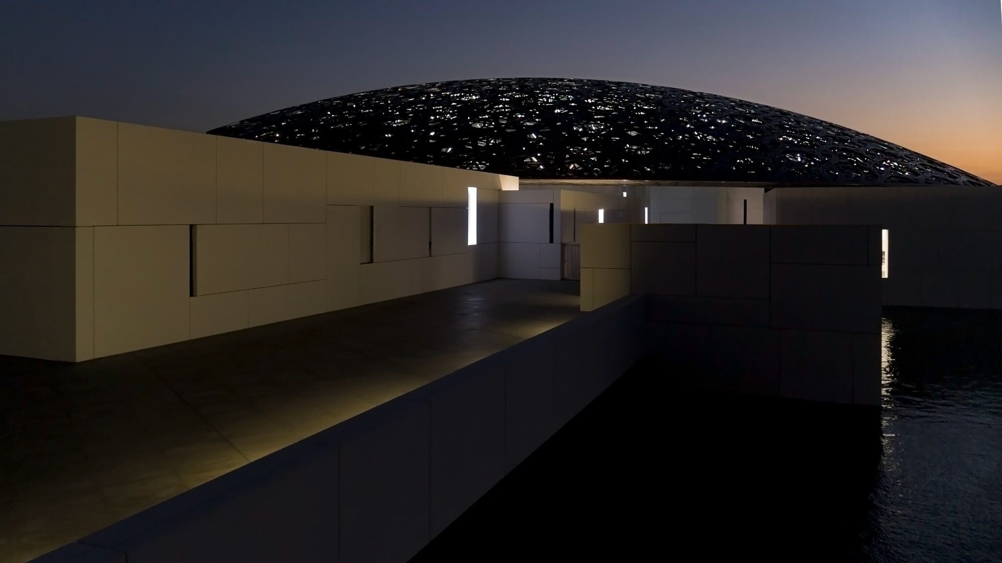 Louvre Abu Dhabi illuminated at night beneath its architectural dome.