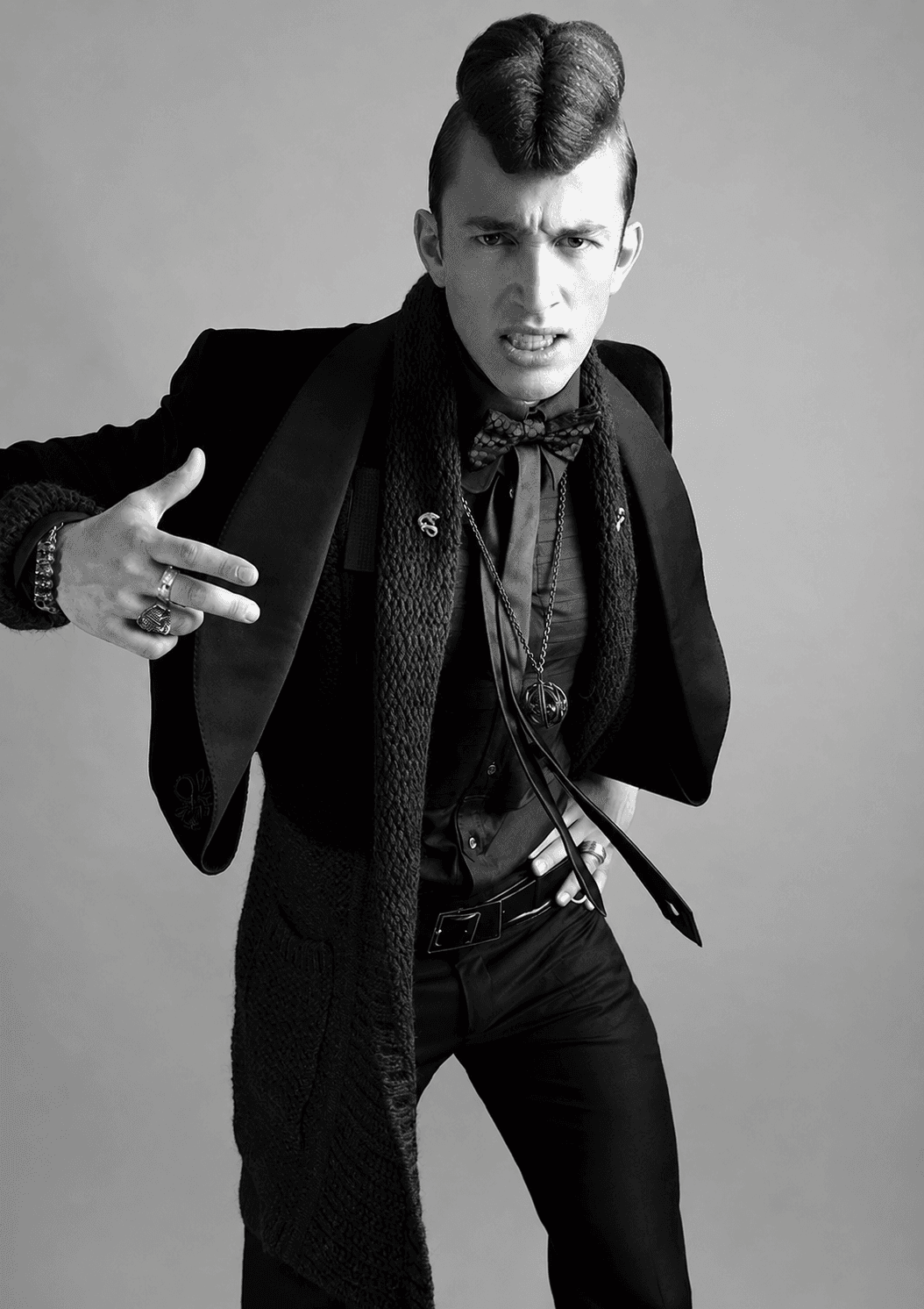 Black-and-white menswear fashion editorial by Toosuns featuring a male model in tailored clothing and statement accessories.